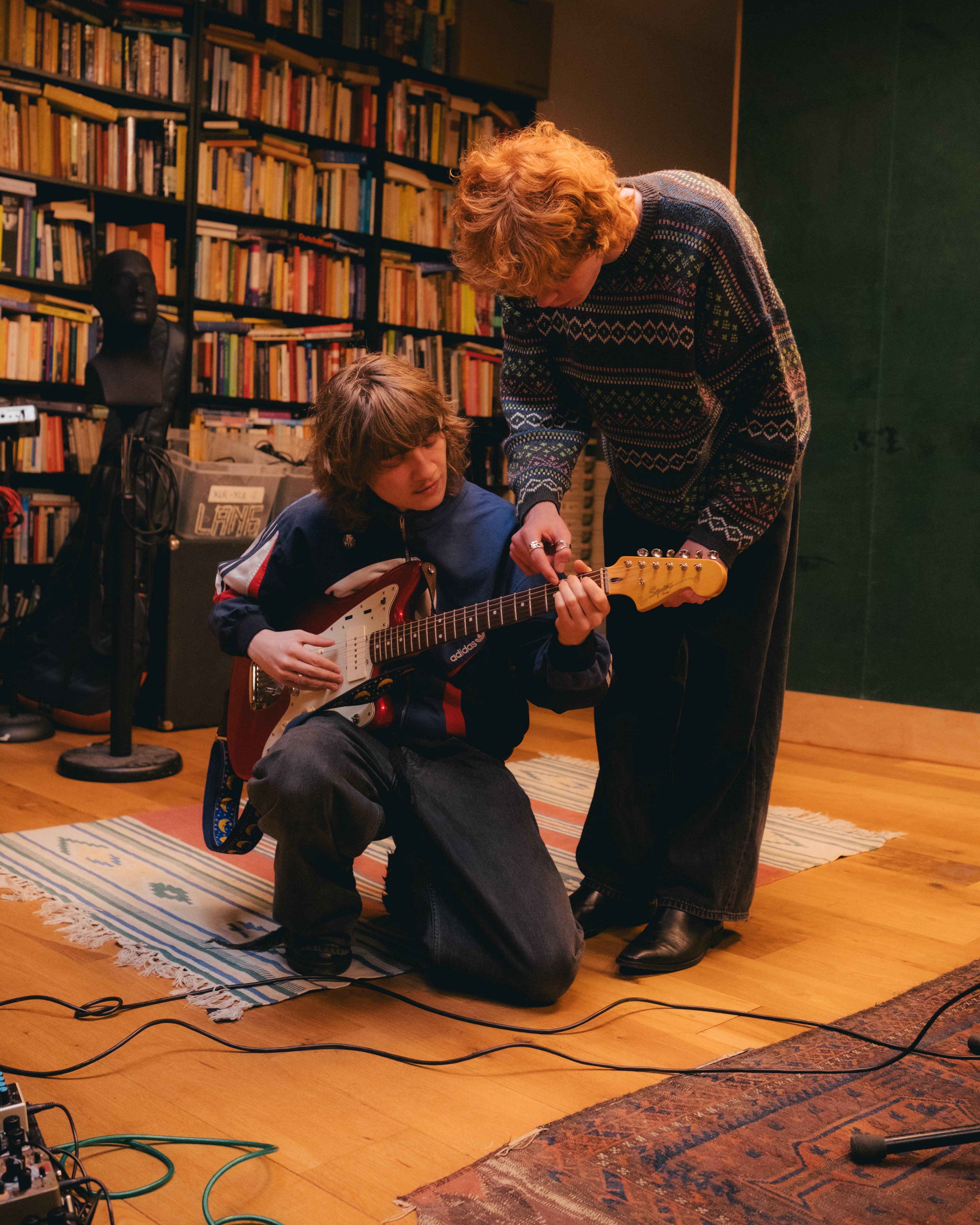 Twee muzikanten staan over een gitaar heen gebogen.